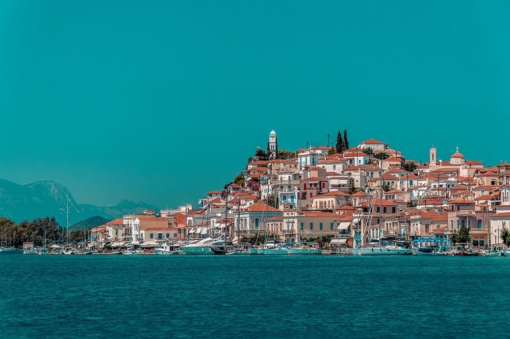 Das malerischer Hafenstädtchen Poros mit dem weißen Kirchturm und tollem Ausblick auf das Festland von Griechenland
