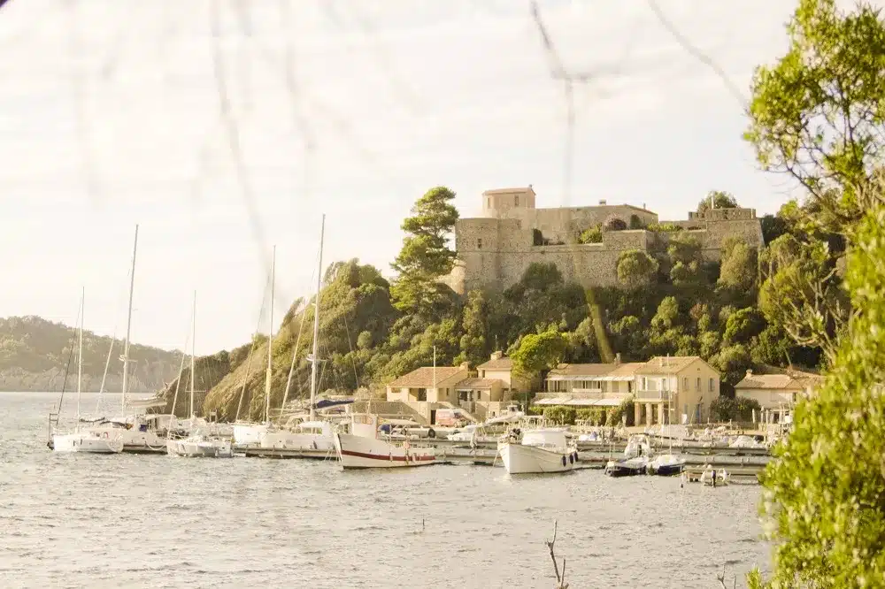Blick von der modernen Yacht auf einen kleiner Hafer der C'ôte d'Azur mit einer Festung im Hintergrund