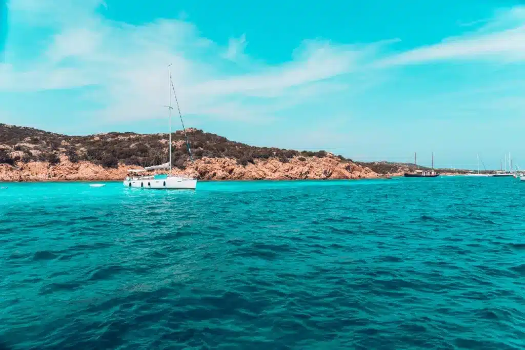 Traumhafte Bucht in Sardinien mit Blick auf die moderne sailwithus Segelyacht