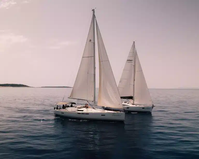 Zwei Segelboote navigieren während eines Segeltörns dicht beieinander auf ruhiger See unter klarem Himmel.